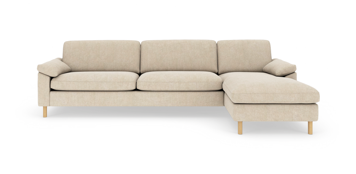 Beige hjørnesofa med chaiselong til højre, slanke træben og neutral stofpolstring.