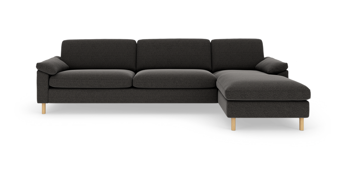 Mørkegrå 3-personers sofa med højrevendt chaiselong og lyse træben i studiemiljø.