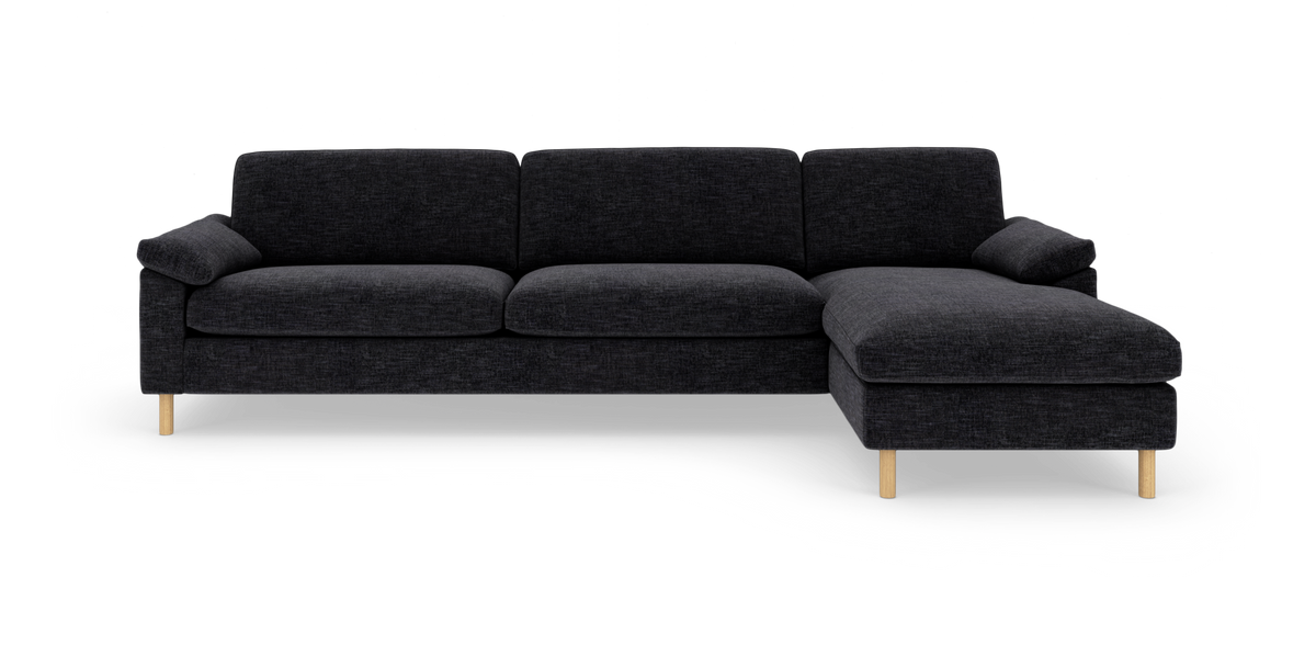 Mørkegrå hjørnesofa med chaiselong til højre på lys baggrund.