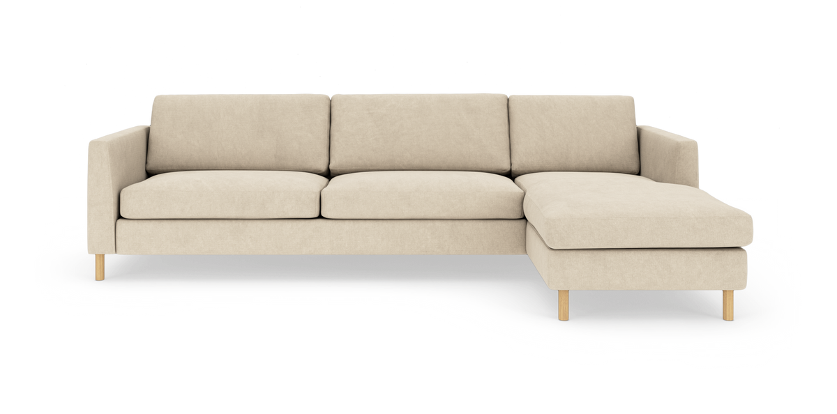 Beige hjørnesofa med chaiselong til højre og træben, frilagt på hvid baggrund.