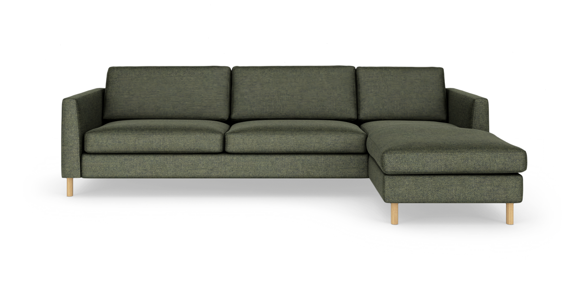 Mørkegrøn 3-personers sofa med chaiselong til højre og lyse træben på hvid studiobaggrund.