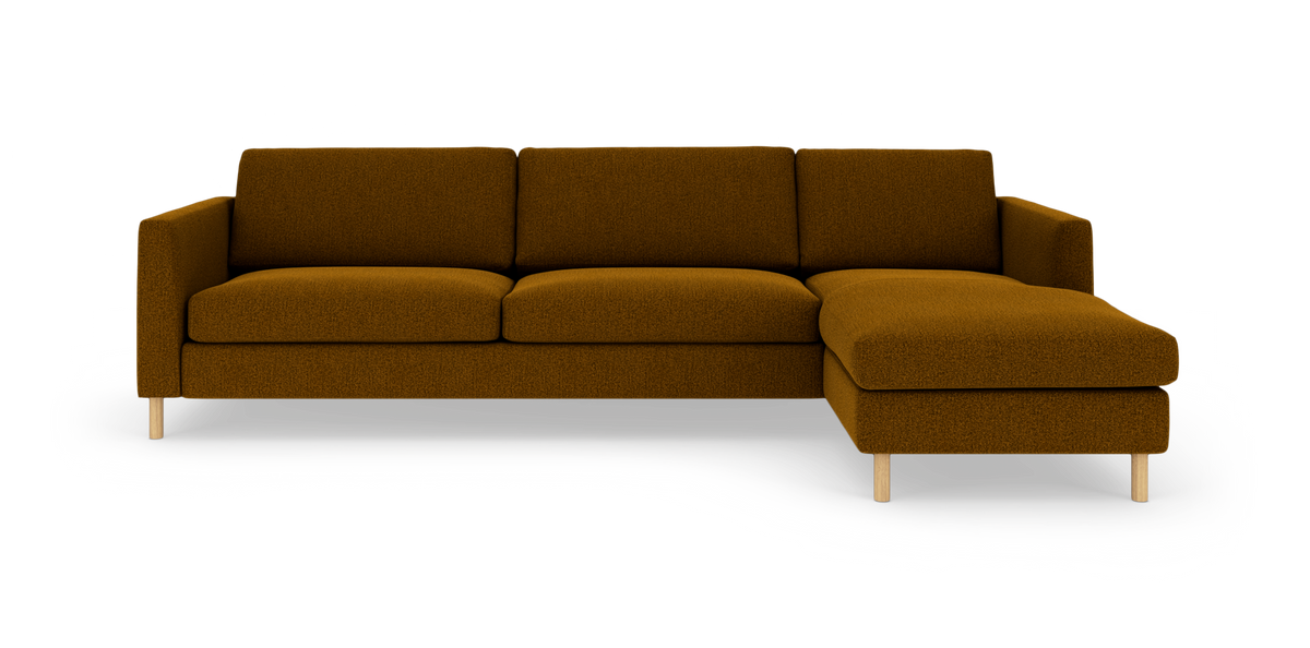 Modulsofa med højre chaiselong i sennepsgul/brun tekstil, set forfra på hvid studiebaggrund.