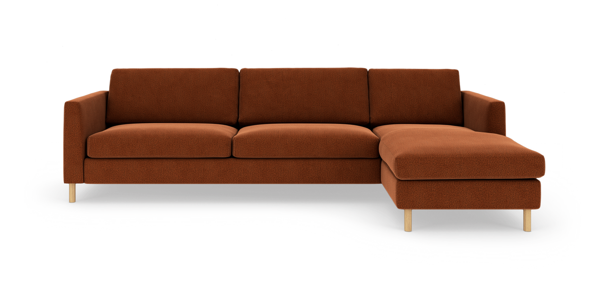 Modulsofa med højre chaiselong i rustfarvet tekstil, lyse træben, frilagt på hvid baggrund, frontvisning.