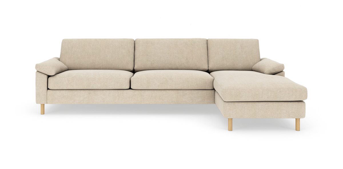 Beige hjørnesofa med højre chaiselong, slanke træben og bløde hynder, frilagt på hvid baggrund.