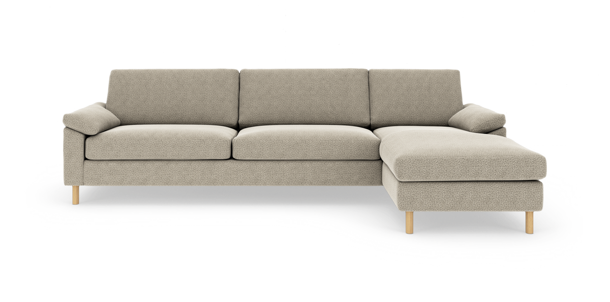Beige modulsofa med chaiselong til højre på hvid baggrund, med træben og bløde puder.