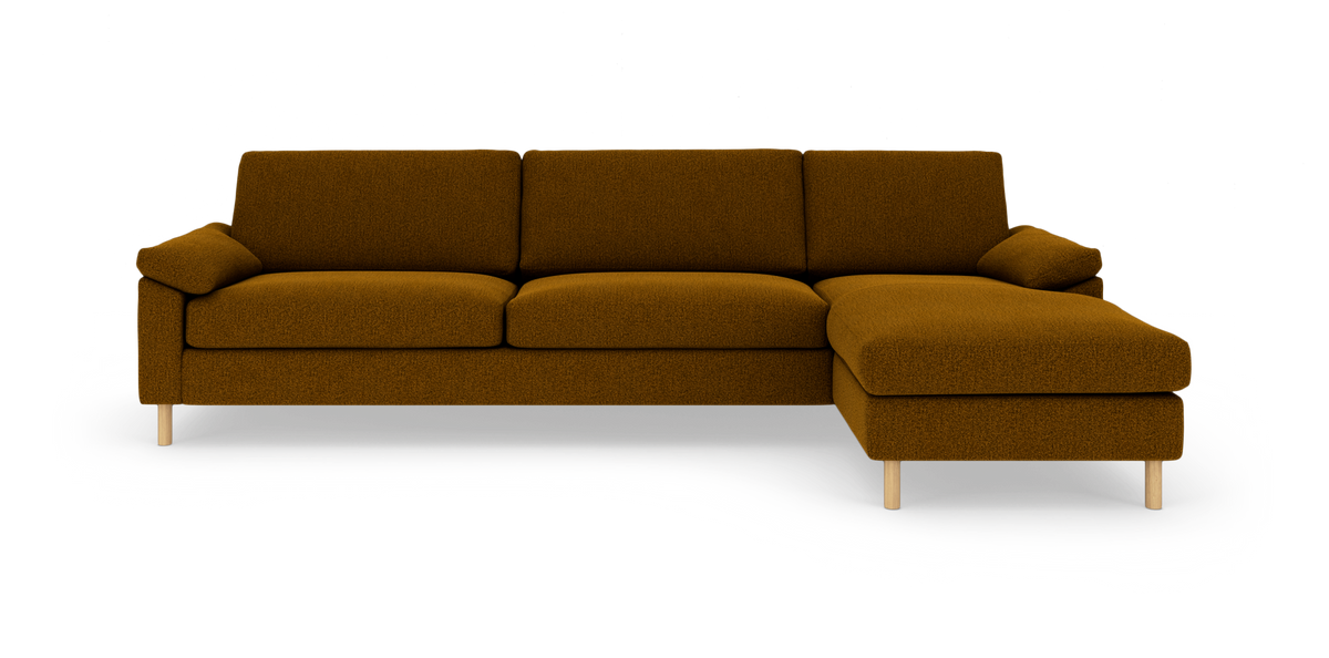 Højrevendt 3-personers sofa med chaiselong i okkerbrunt stof og lyse træben, frilagt på hvid baggrund.