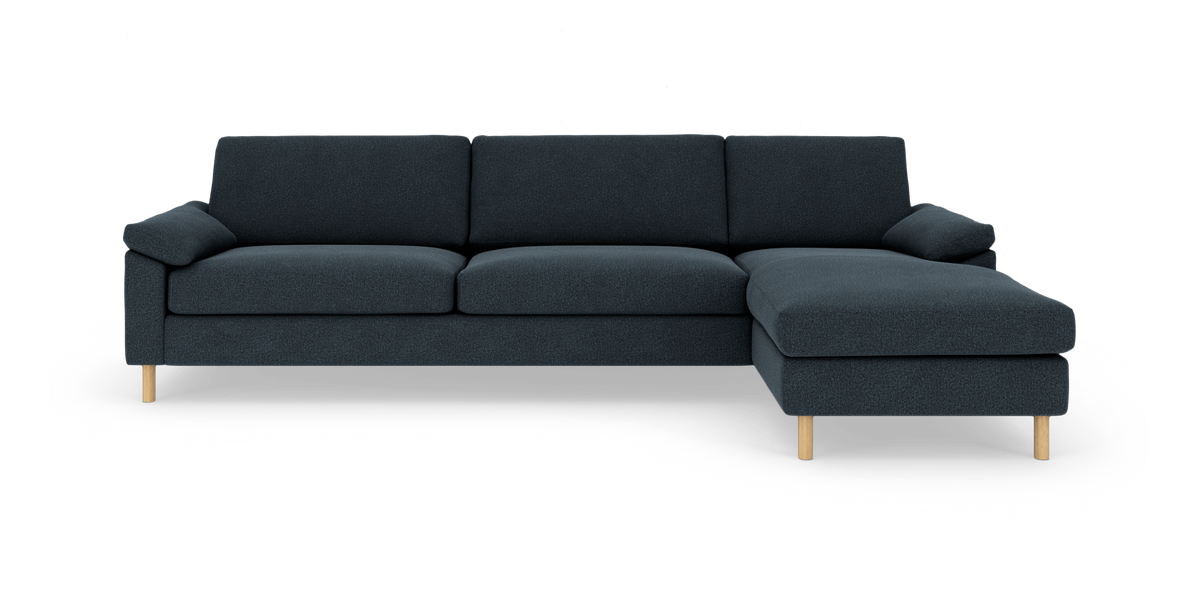 Mørkeblå modulsofa med højre chaiselong og lyse træben, frilagt på hvid baggrund.