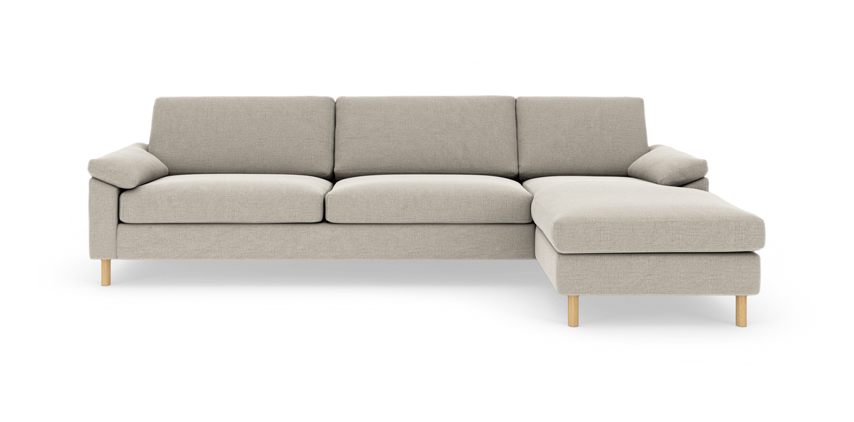 Beige modulsofa med højrevendt chaiselong og træben, fotograferet mod hvid studiebaggrund.