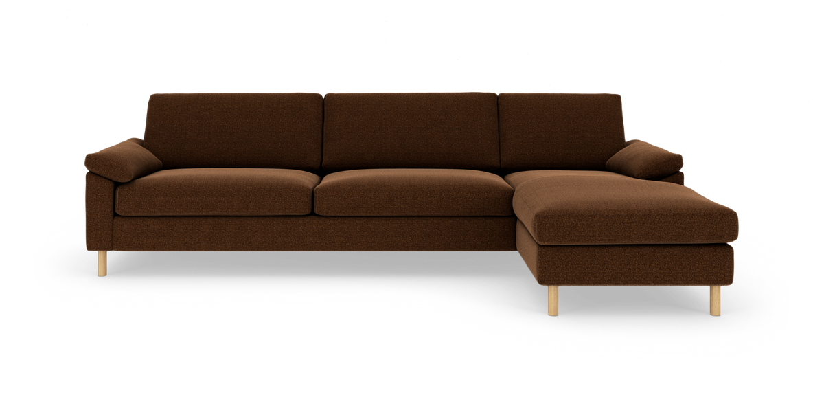 Brun 3-personers sofa med højre chaiselong og lyse træben, fotograferet direkte forfra i studie på hvid baggrund.