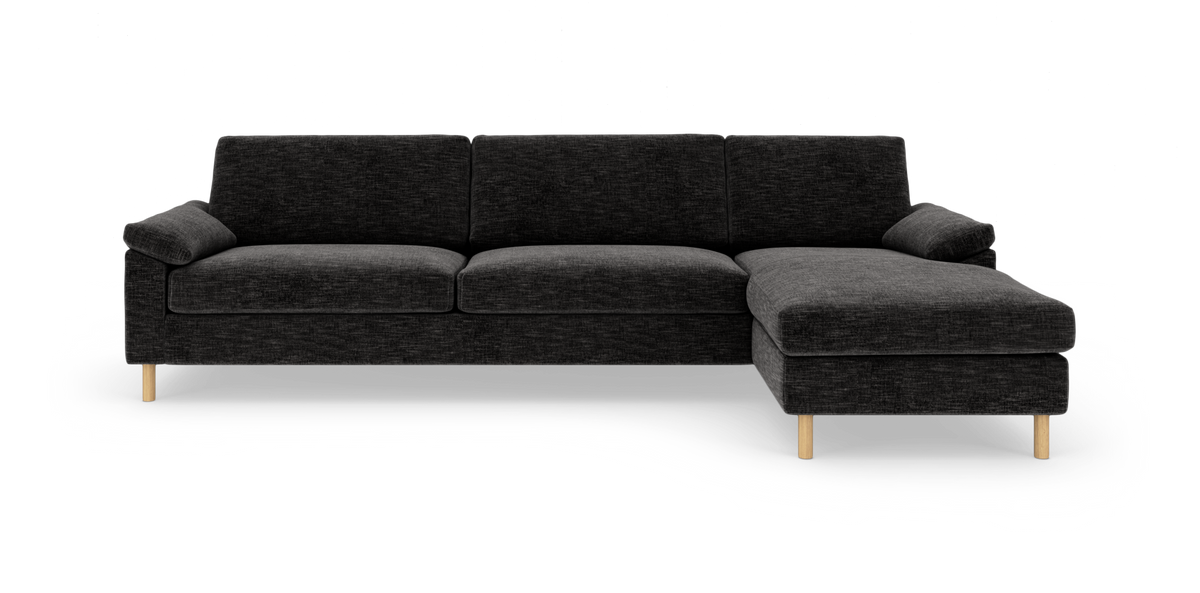 Mørkegrå hjørnesofa med højrevendt chaiselong og lyse træben på hvid baggrund.