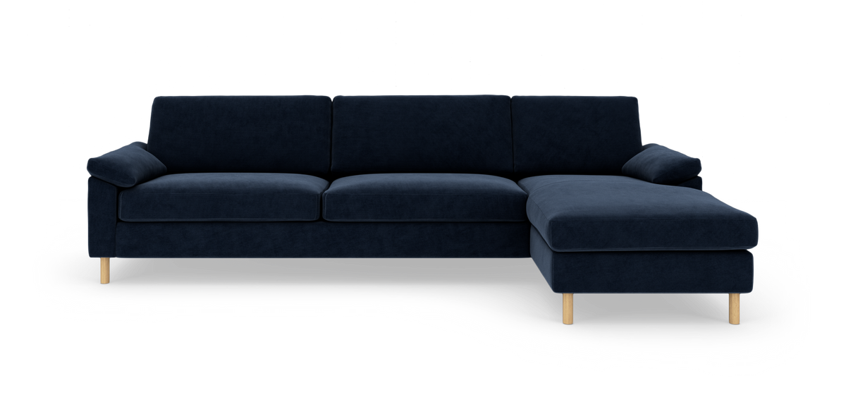 Mørkeblå hjørnesofa med højrevendt chaiselong og lyse træben, frilagt på hvid baggrund.