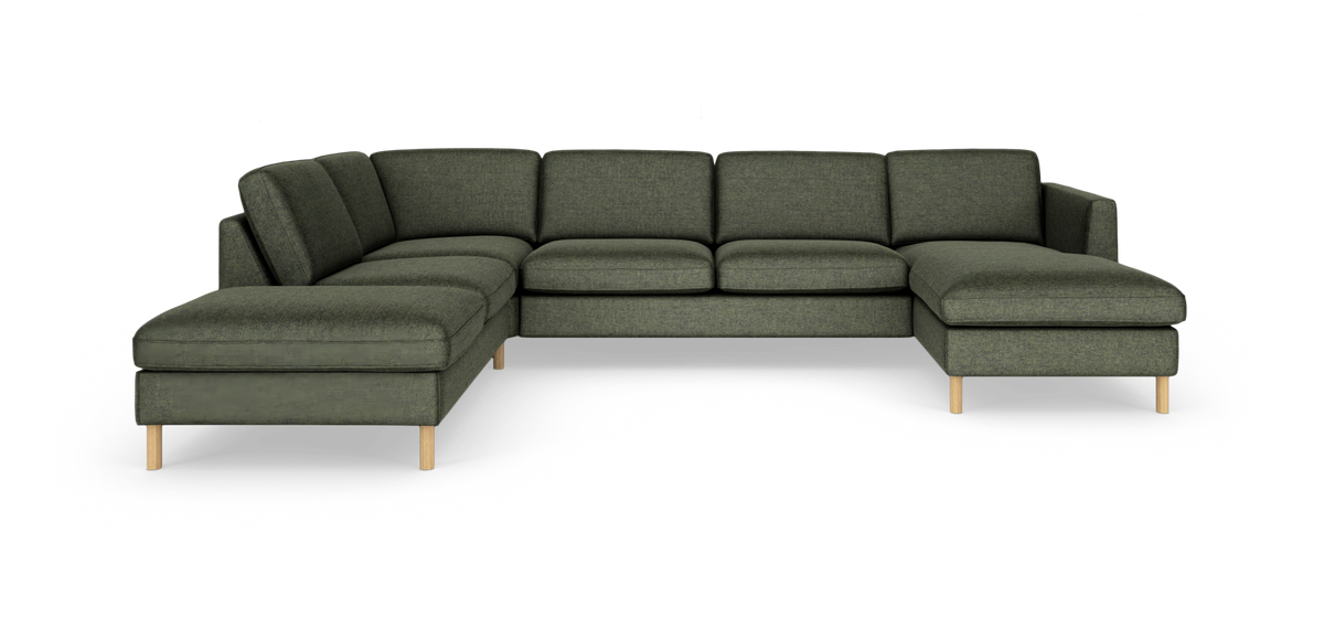 Modulær grøn hjørnesofa med chaiselong og træben i studieopsætning.