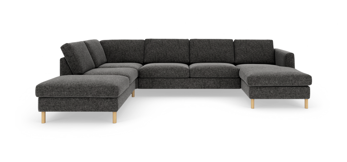 Stor hjørnesofa i mørkegråt stof med chaiselong til højre og lyse træben, fritlagt produktbillede på hvid baggrund.