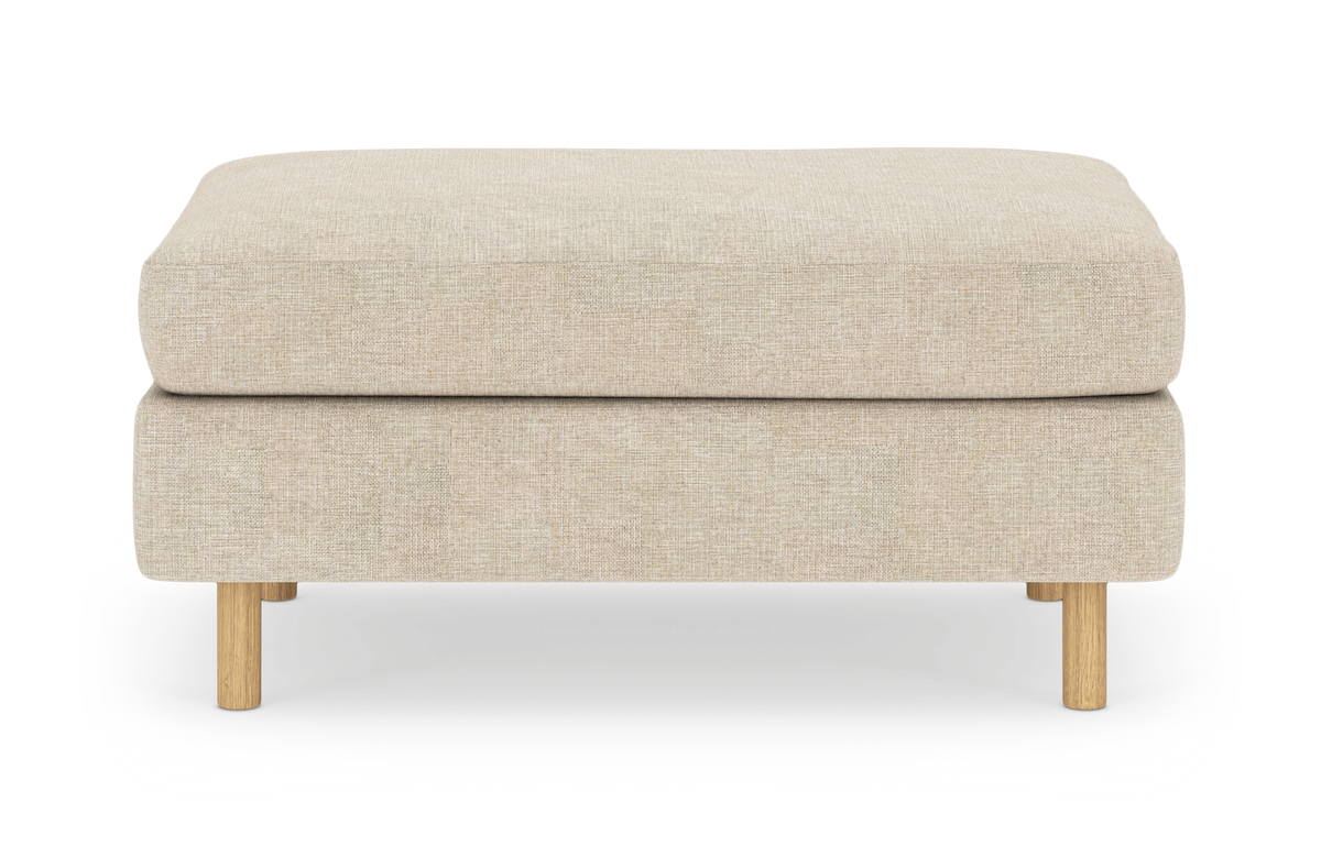 Beige ottoman/fodskammel med runde træben, set forfra mod hvid baggrund.