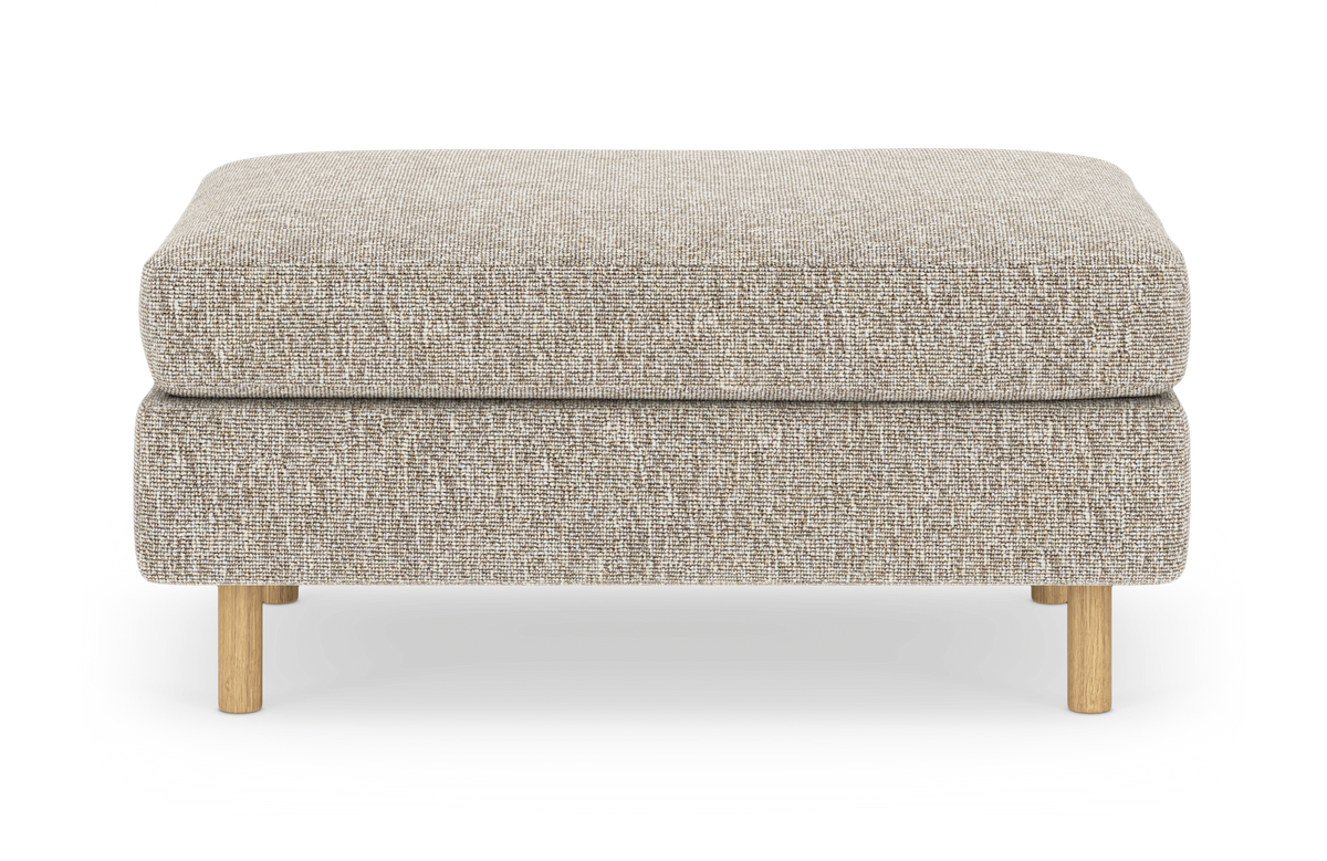 Beige skammel/ottoman i tekstil med lyse træben, isoleret på hvid baggrund.