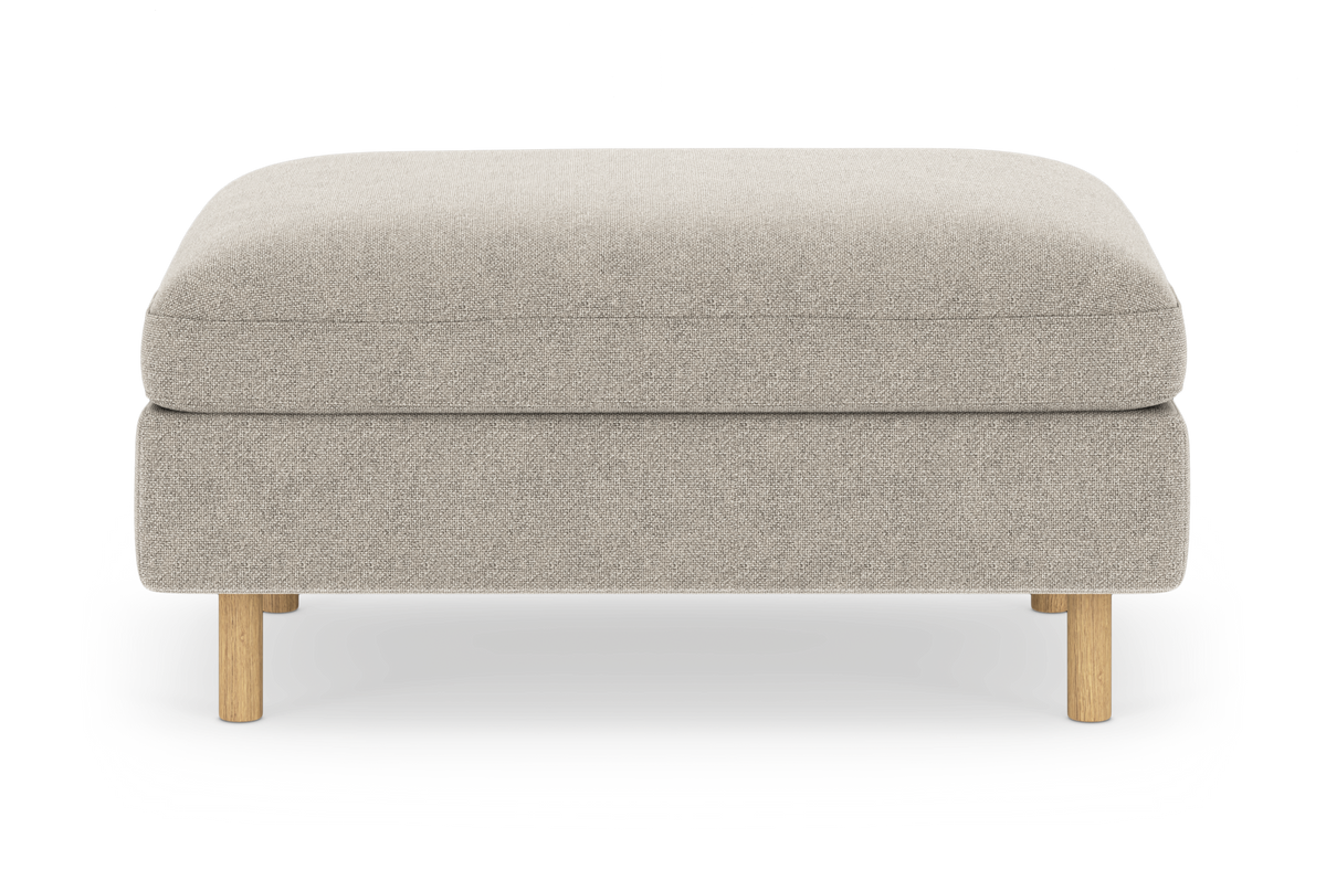 Beige puf/ottoman i stof med lyse træben, frilagt på hvid baggrund.