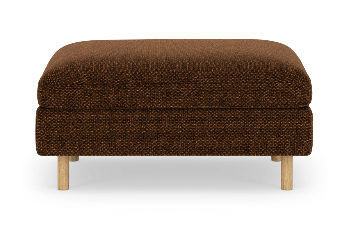 Brun stofpuf/ottoman med lyse træben, isoleret på hvid baggrund.