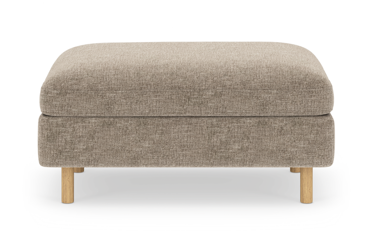 Beige stofpolstret ottoman/puf med afrundede kanter og runde ben i lyst træ, centreret på hvid baggrund.
