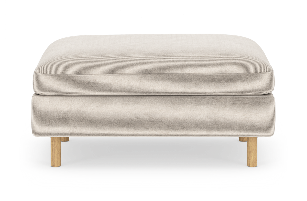 Beige puf/ottoman i stof med runde træben, frilagt på hvid baggrund.