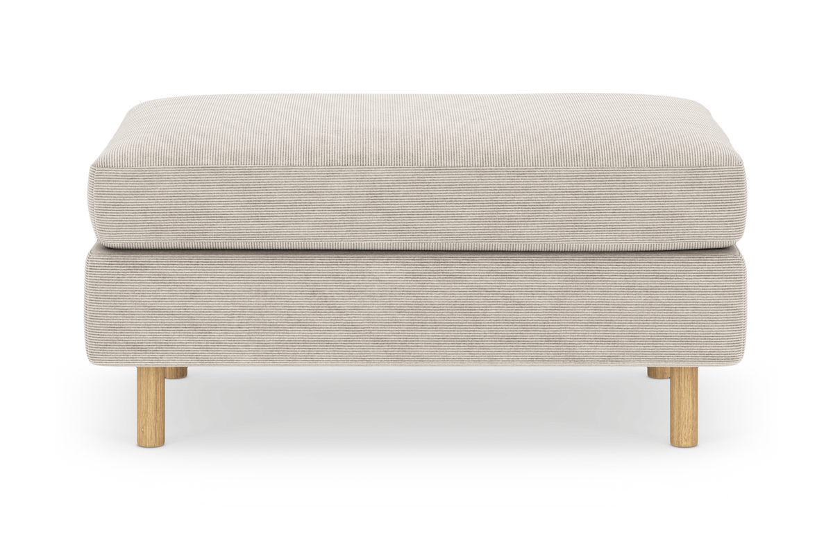 Beige puf i riflet stof med runde træben, fotograferet lige for mod hvid baggrund.