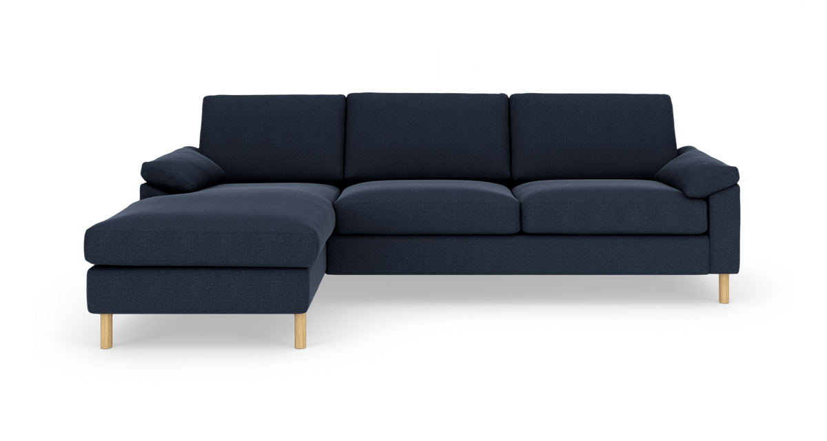 Mørkeblå hjørnesofa med chaiselong til venstre på træben, frilagt på hvid baggrund.