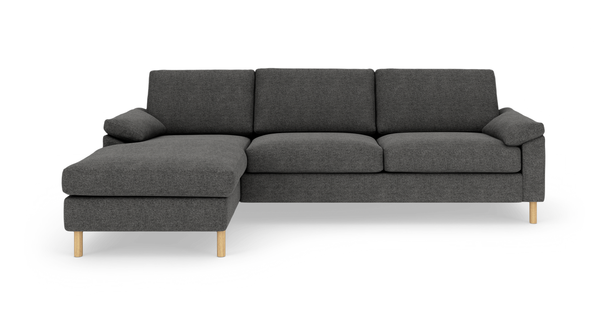 Mørkegrå hjørnesofa med venstrevendt chaiselong og lyse træben, frilagt på hvid baggrund.