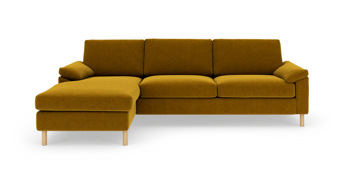 Sennepsgul venstrevendt hjørnesofa med chaiselong og lyse træben, frilagt på hvid baggrund.