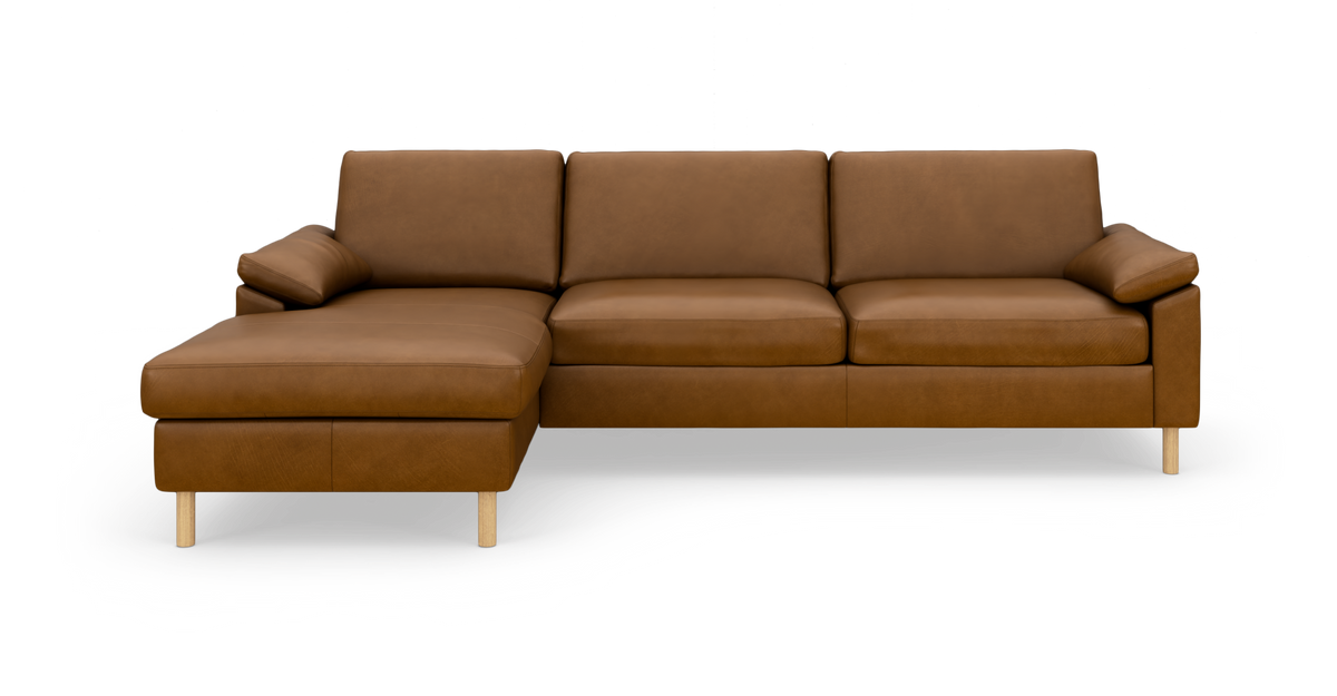Brun hjørnesofa i læder med venstrevendt chaiselong, på runde træben, frontvisning mod hvid baggrund.