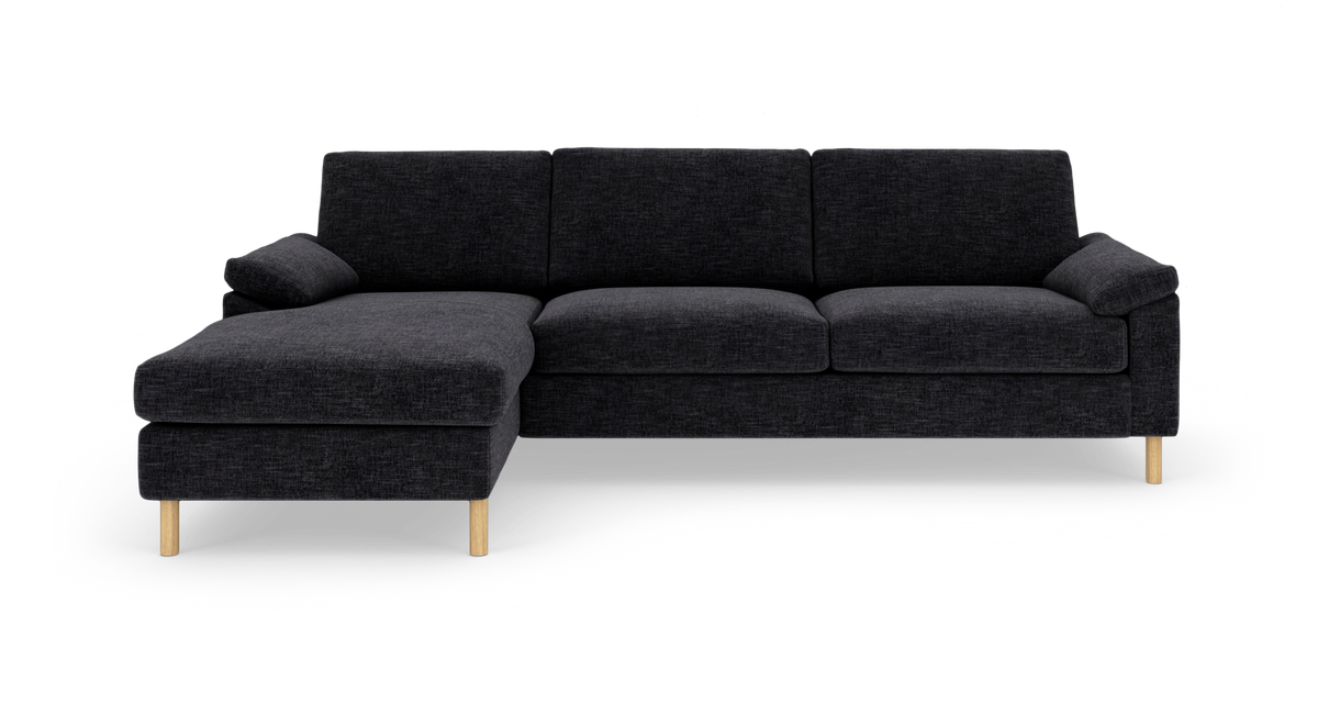 Sort modulsofa med venstre chaiselong og lyse træben, frilagt på hvid baggrund.