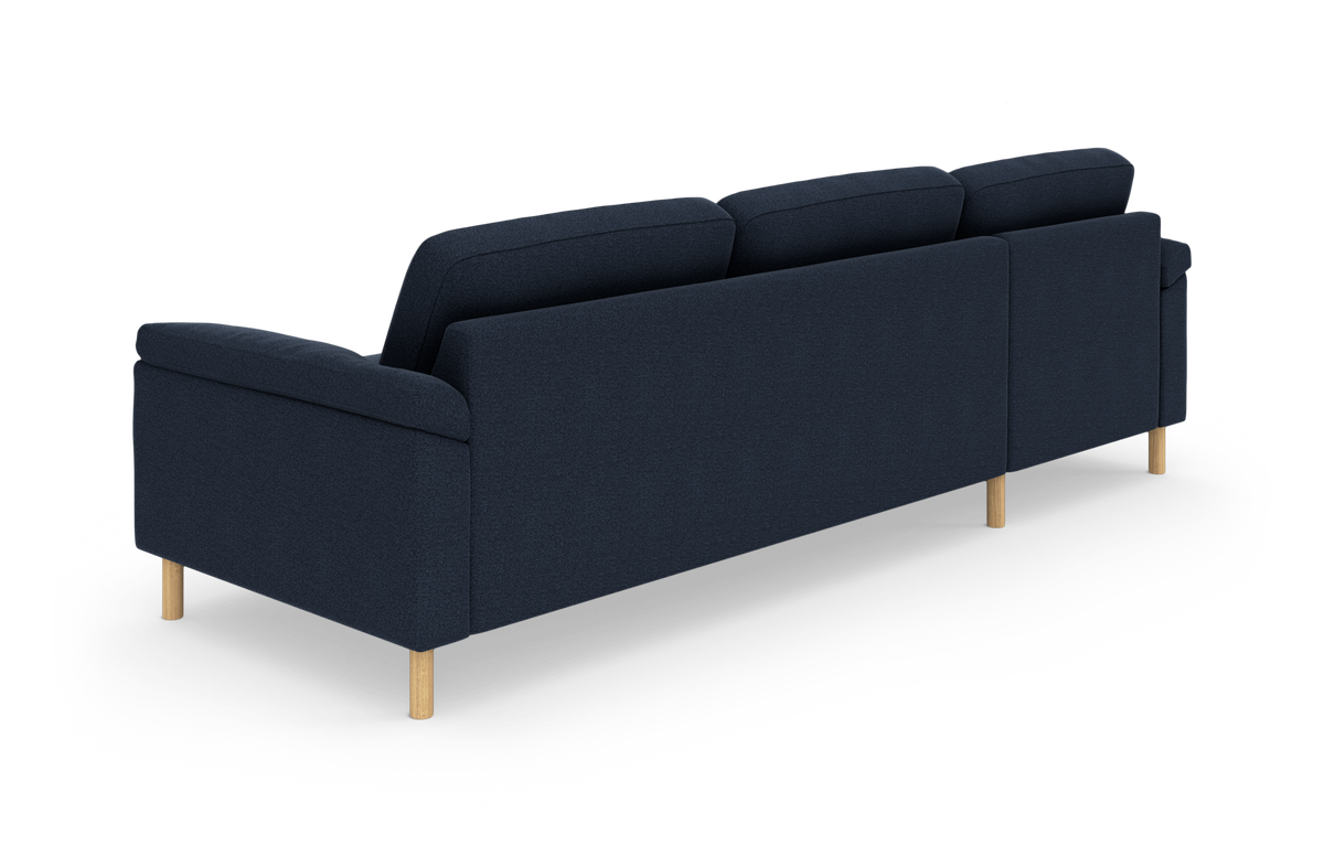 Mørkeblå tresæders sofa set skråt bagfra med lyse træben på hvid baggrund.