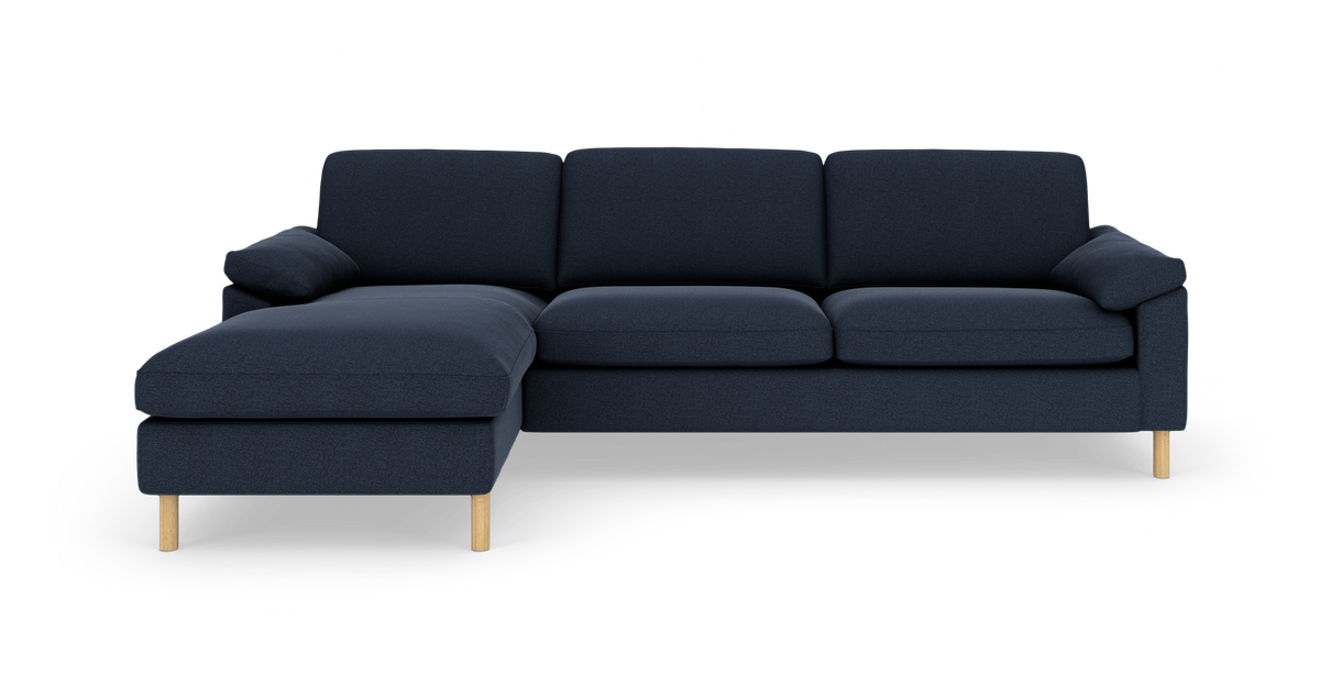 Mørkeblå hjørnesofa med venstrevendt chaiselong og lyse træben, fritstående på hvid baggrund.