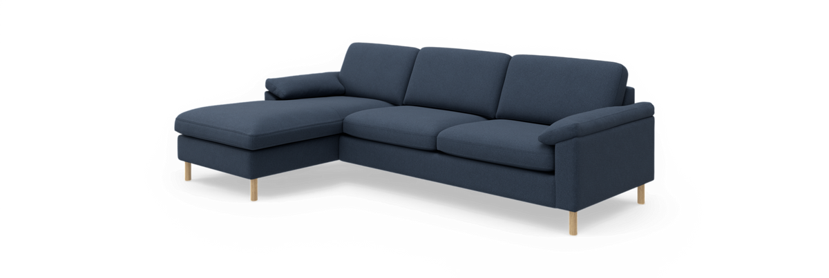 Mørkeblå hjørnesofa med venstrevendt chaiselong og lyse træben, frilagt på sort baggrund.
