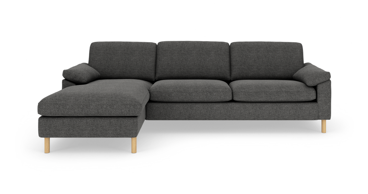 Mørkegrå hjørnesofa med venstrevendt chaiselong og lyse træben, set forfra mod hvid baggrund.