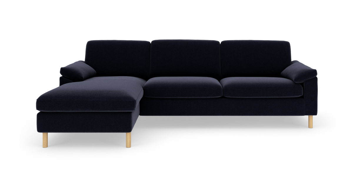 Mørkeblå hjørnesofa med venstrevendt chaiselong og lyse træben, frilagt mod hvid baggrund.