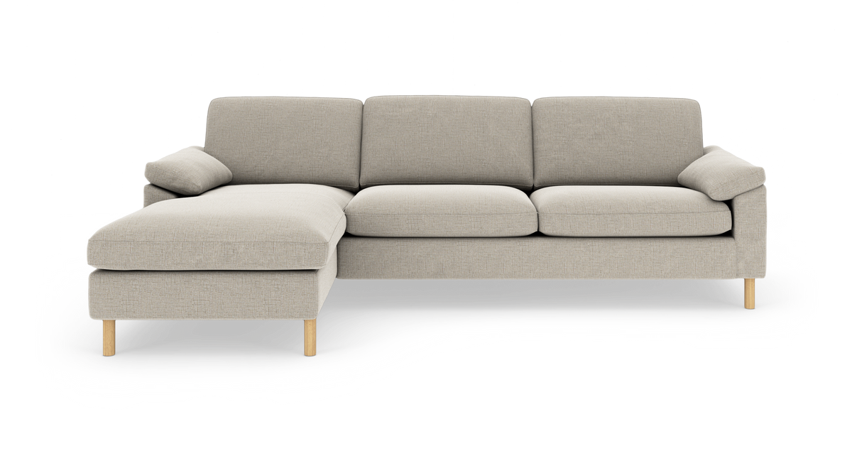 Lys beige hjørnesofa med venstre chaiselong, bløde puder og lyse træben; frontvisning i studie.
