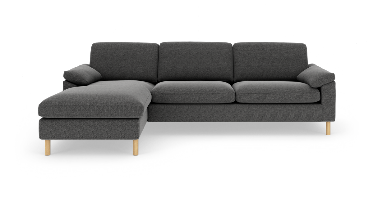 Mørkegrå hjørnesofa med venstrevendt chaiselong og lyse træben, set forfra i studieopsætning.