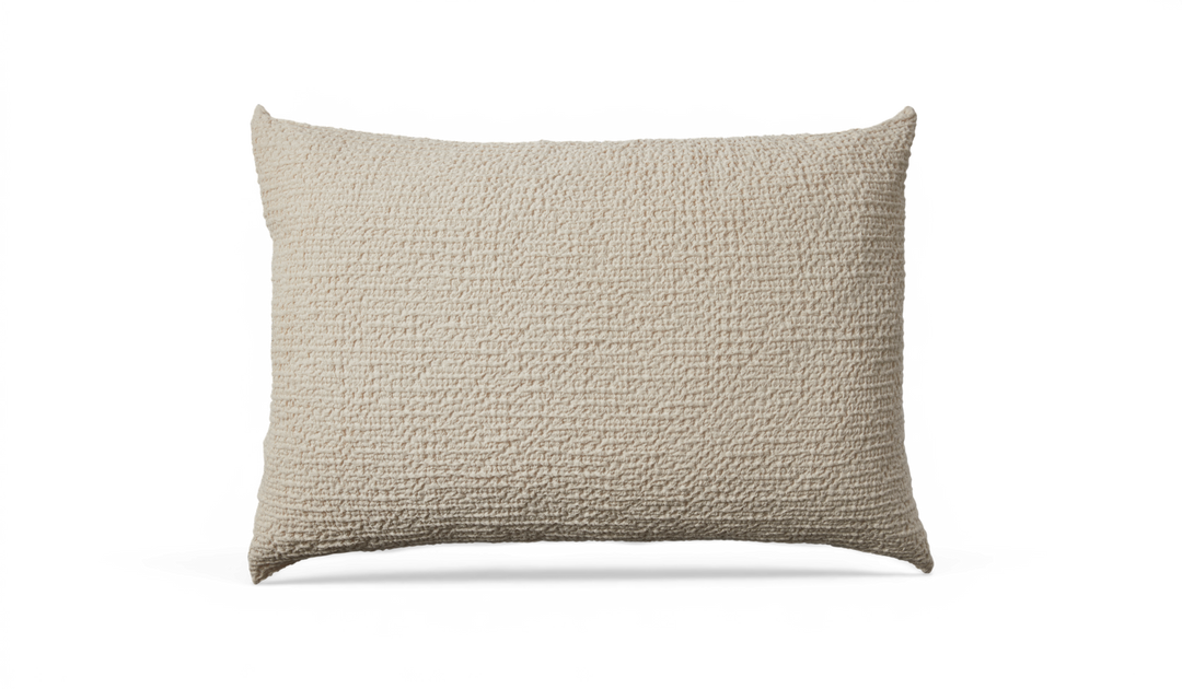 Beige rektangulær pude med grov, vævet tekstur.