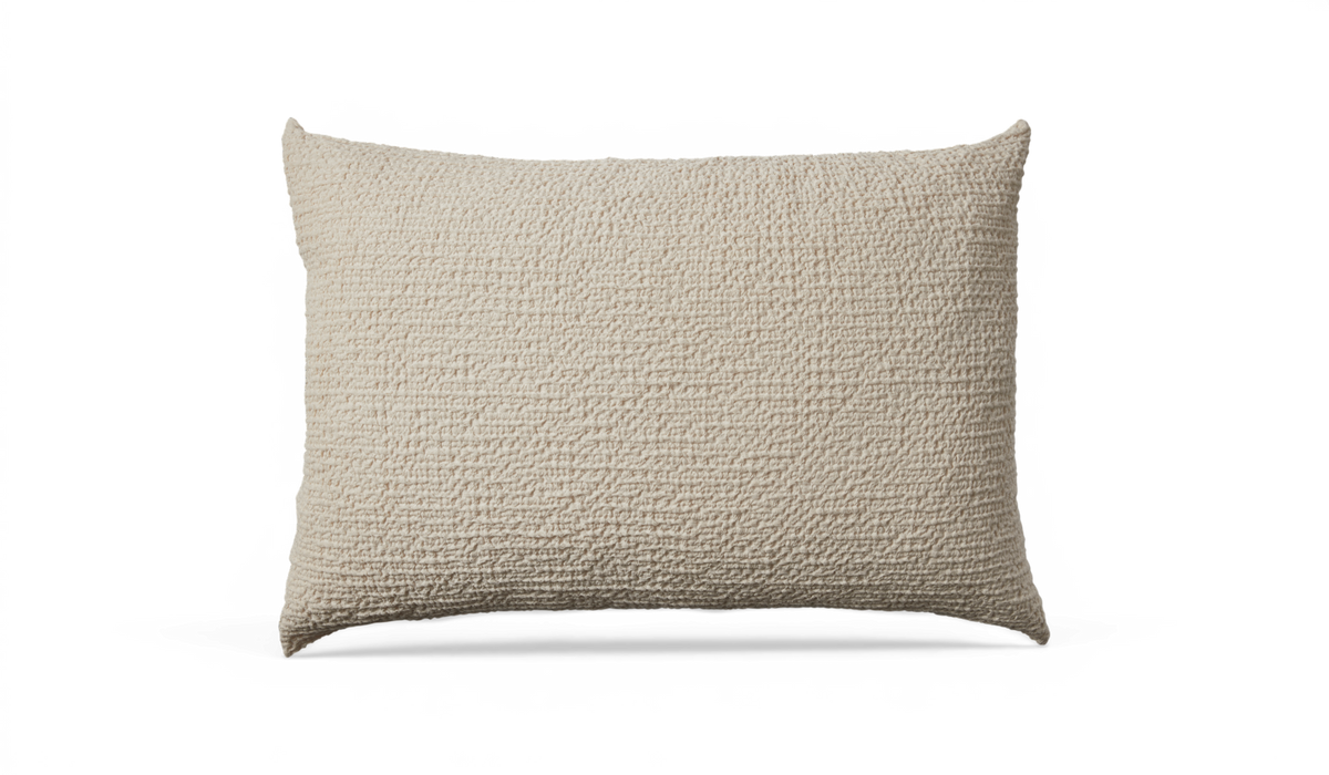 Beige rektangulær pude med grov, vævet tekstur.