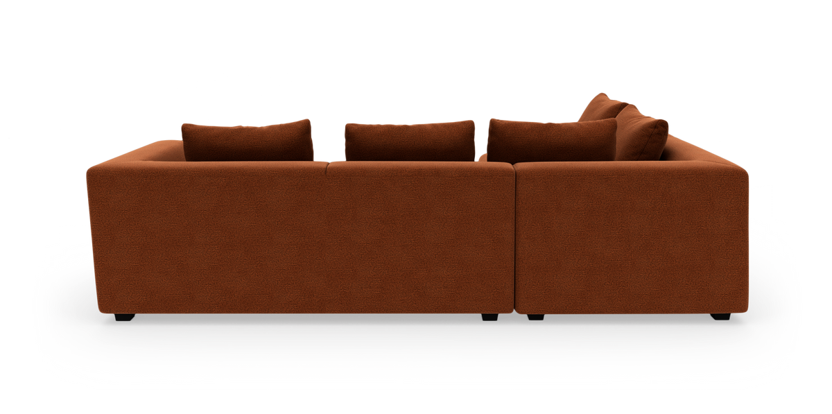 Rustfarvet modulsofa set bagfra i studio, bred rektangulær form med fire rygpuder.