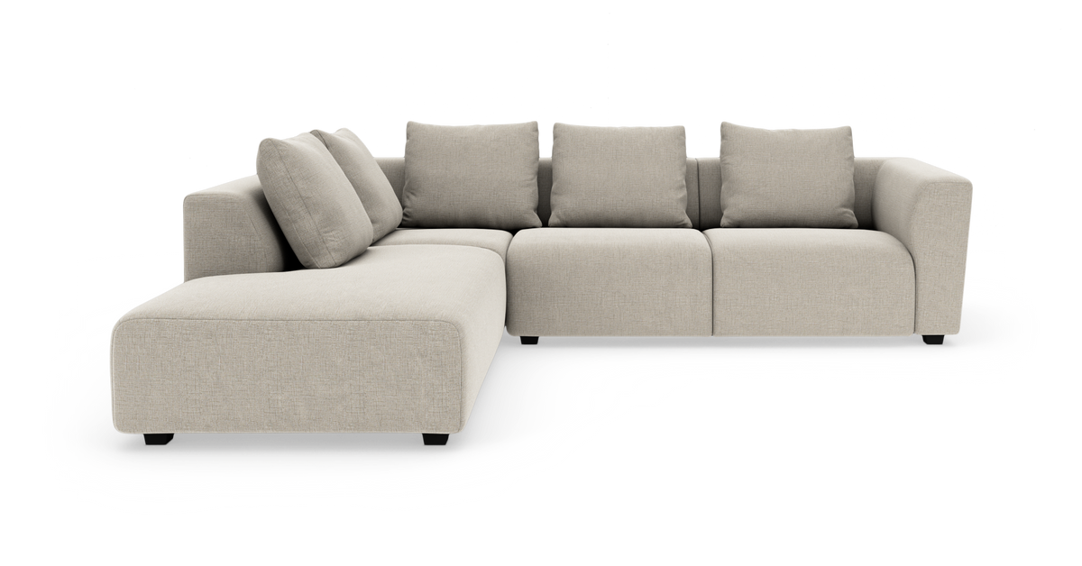Beige modulsofa i L‑form med fire rygpuder og bred chaiselong.