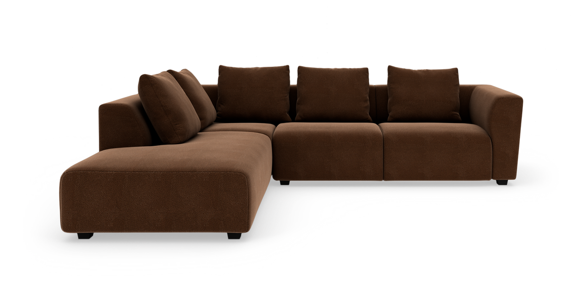 Brun modulsofa i L‑form med bred chaiselong og bløde rygpuder, frilagt på hvid baggrund.