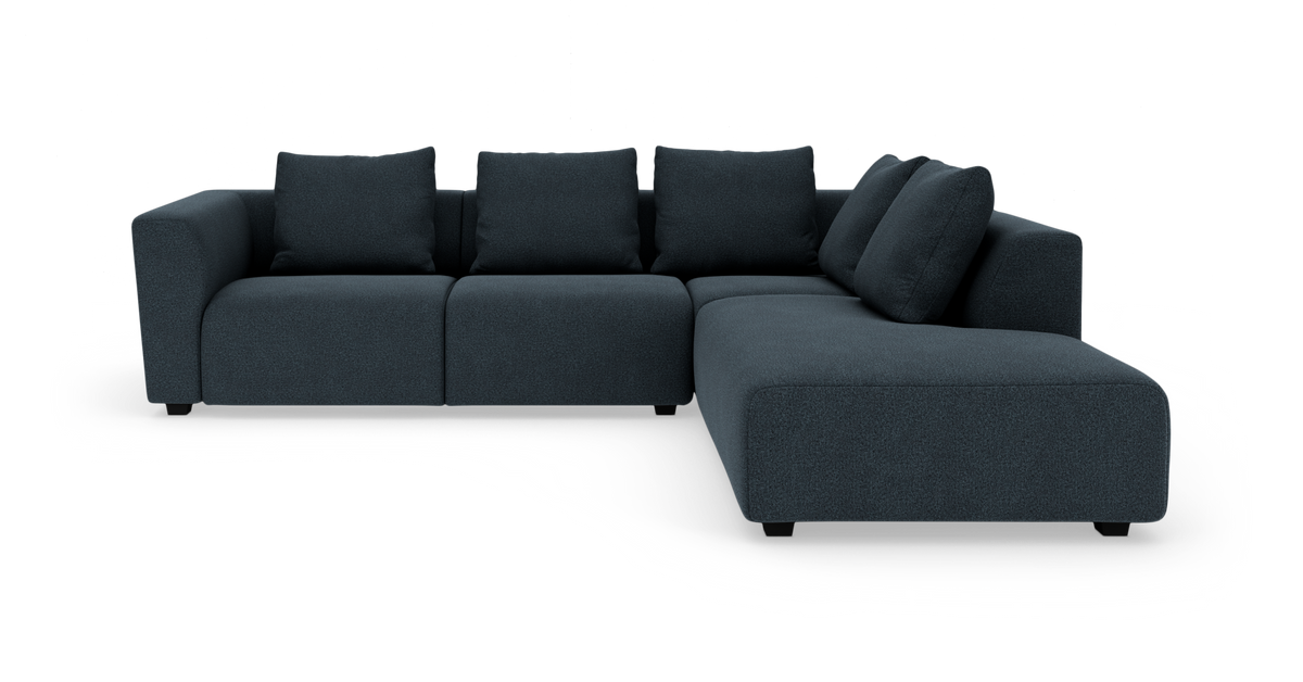 Mørk blå L-formet modulsofa med chaiselong til højre på hvid baggrund.