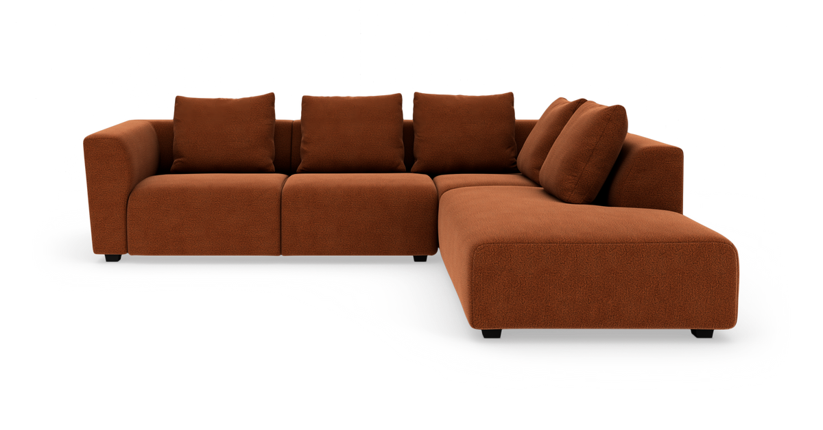 Modulær hjørnesofa i rust-rød tekstil med chaiselong til højre, fire ryghynder og bløde, afrundede armlæn.