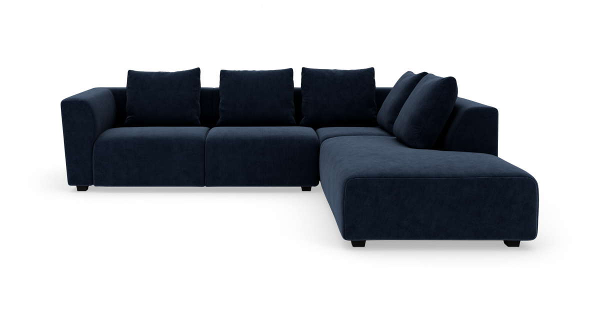 Mørkeblå modulsofa i vinkel med chaiselong til højre, frilagt på hvid baggrund.