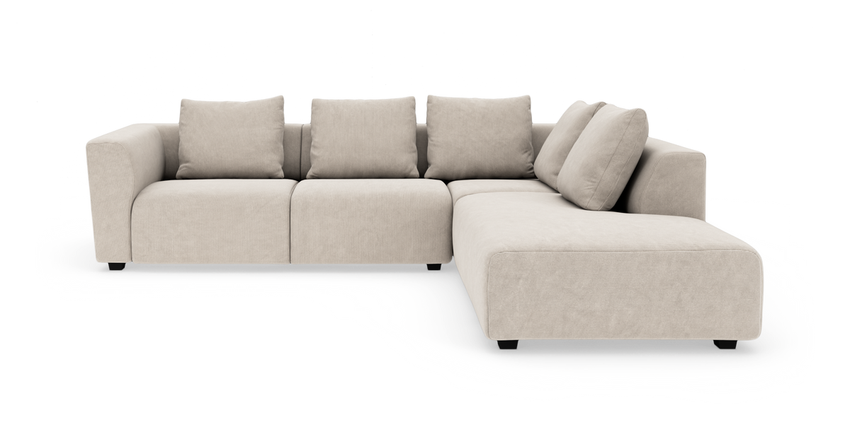 Beige modulsofa i L-form med chaiselong til højre, fire ryghynder og brede armlæn, frilagt på hvid baggrund.
