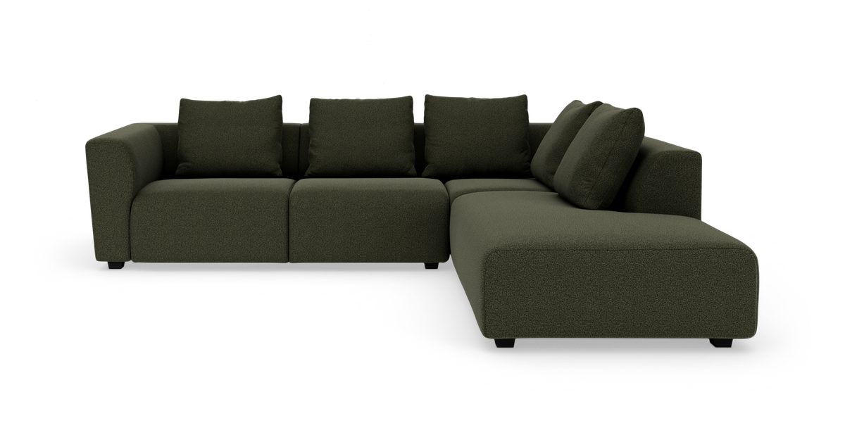 Mørkegrøn modulsofa i L‑form med chaiselong til højre, set forfra i studieopsætning.