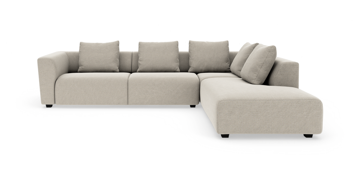 Beige modulsofa i L‑form med højre chaiselong og fem rygpuder, afrundede armlæn, moderne design på hvid baggrund.