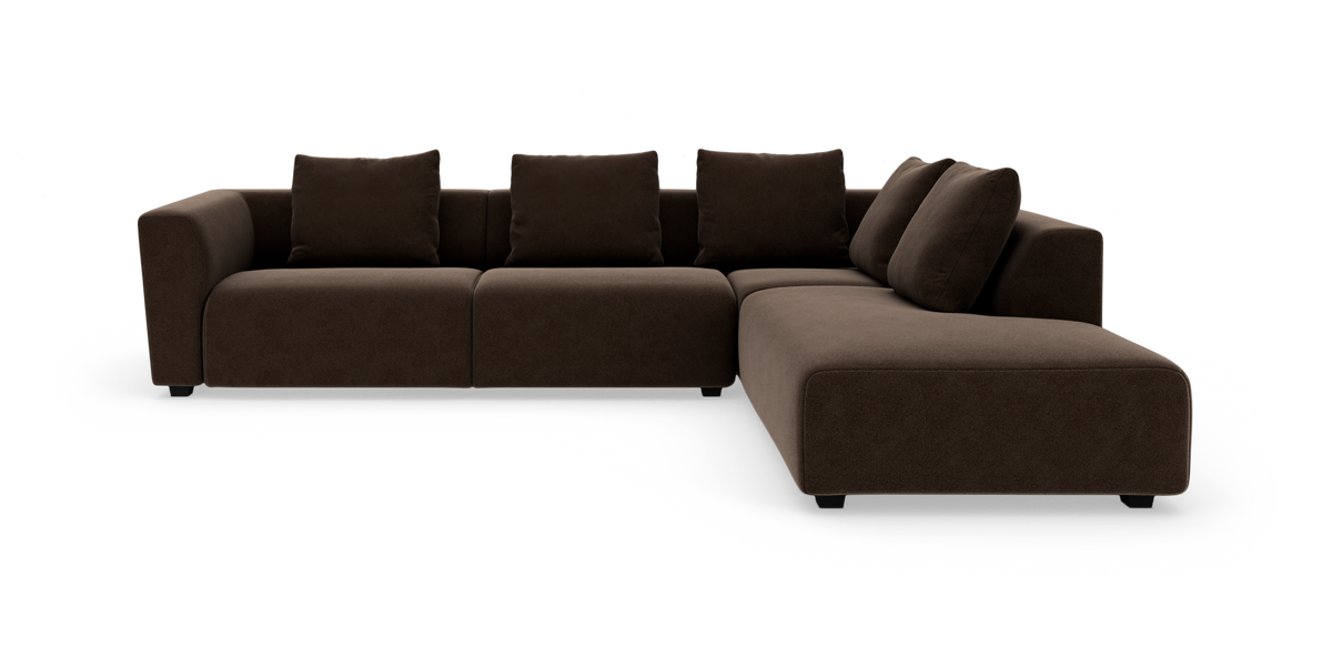 Mørkebrun L‑sofa med chaiselong til højre og løse rygpuder, frilagt mod hvid baggrund.