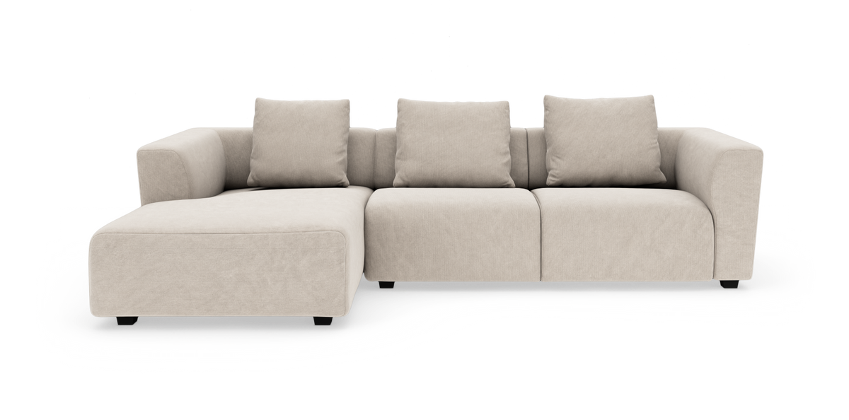 Beige modulsofa med chaiselong til venstre og tre rygpuder på hvid baggrund.