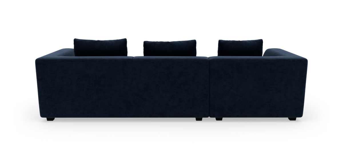 Mørkeblå sofa med tre rygpuder set bagfra mod hvid baggrund.